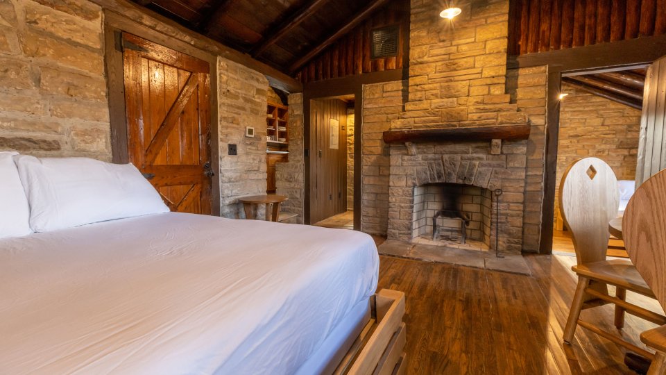 bedroom stone fireplace with small dining table and overhead lighting