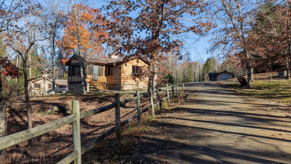 driveway to fenced in wooden shingle cabin 