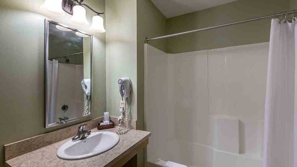 Bathroom with shower tub, sink with counter space, telephone, and mirror with lights above