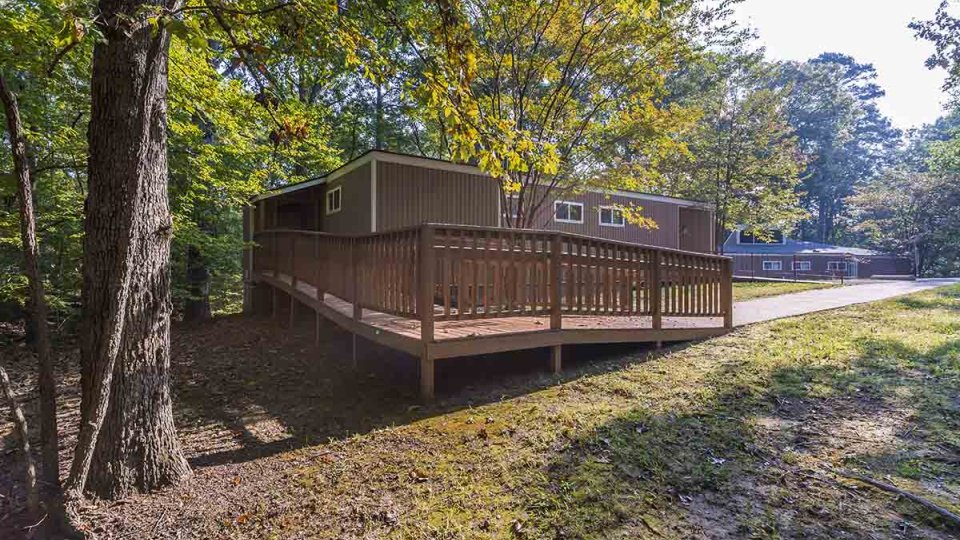 Wooden ramp that leads to a door of a brown cabin