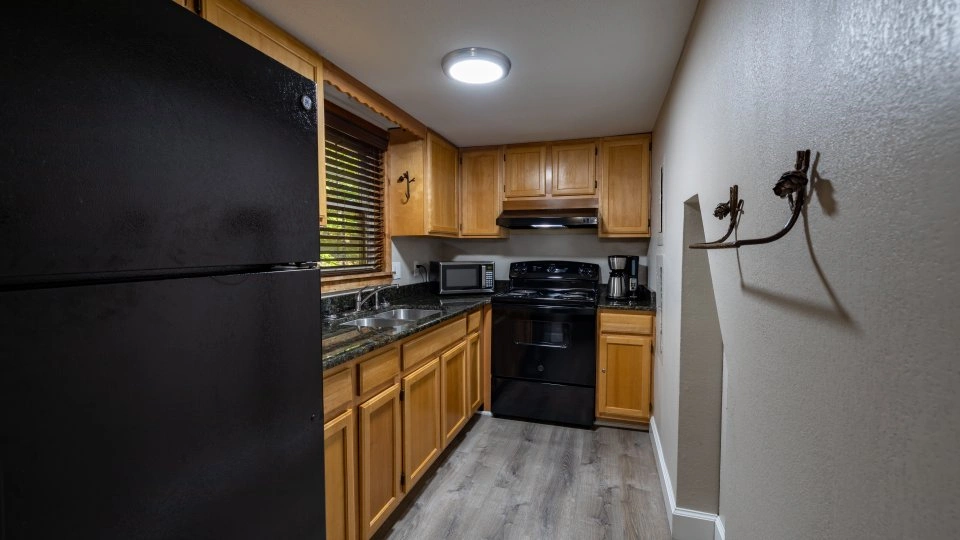 Cabin kitchen with wood cabinetry, white appliances, and a small dining nook.