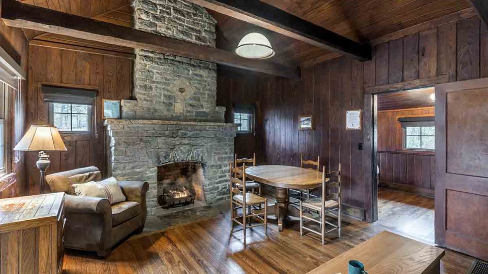 rustic cabin, stone fireplace in living room with small dining table