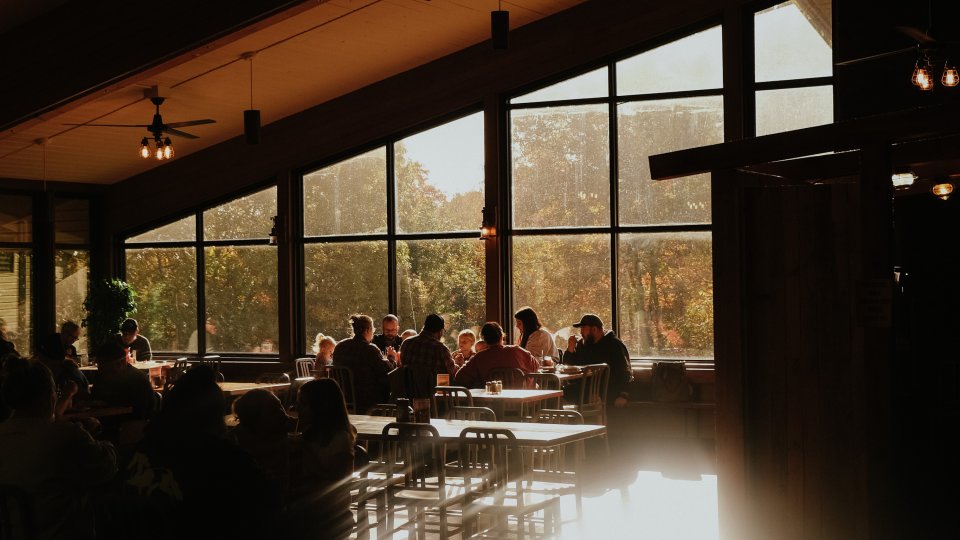 light streaming in from the back windows while families eat in the dining room of the restaurant