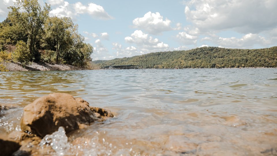 lakeshore water splashing on the nearby rocks with a landscape view of the hills