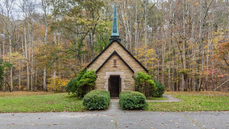 small church with bushes on the side and trees behind it