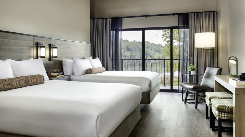 bedroom with two queen sized beds, modern lighting, a glass door leading to a patio, chairs, and a desk