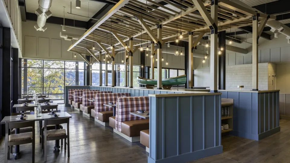 Inside a restaurant with wooden aesthetic, wooden tables and booths, and a canoe in the middle of the room raised up