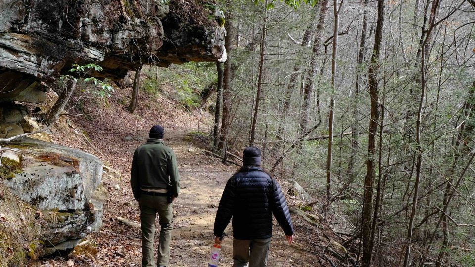 two people walking down a natural trail in the fall wearing winter jackets