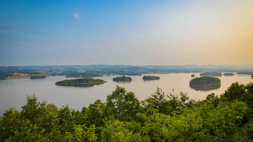 view of multiple small bodies of land on water with the sun beginning to set