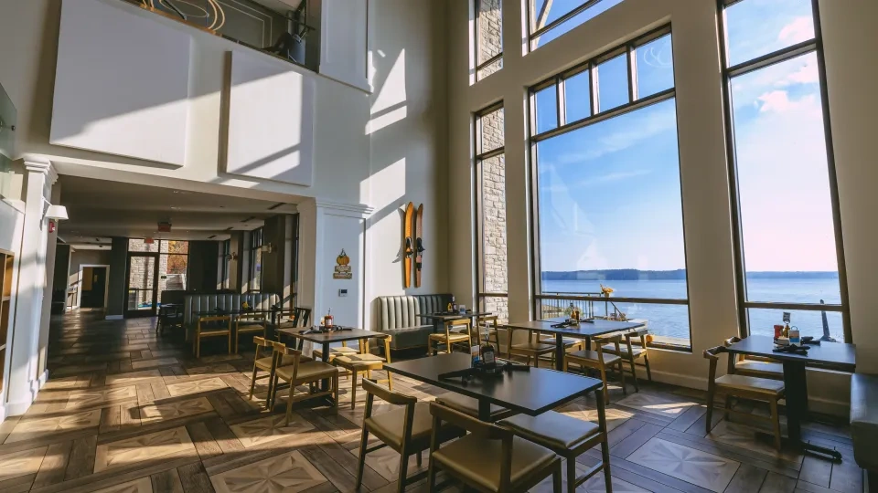 Bright restaurant with large windows overlooking a lake.