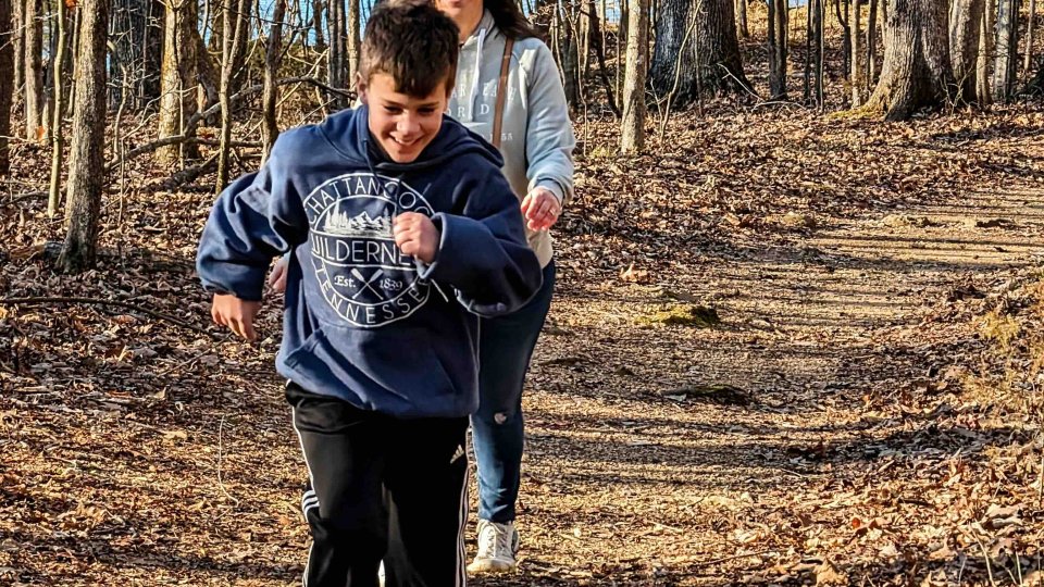boy and woman walking down a trail in the fall