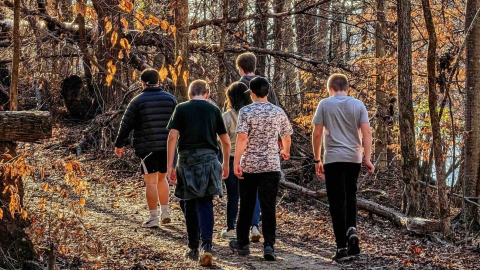 group of boys walking down a natural trail with a woman