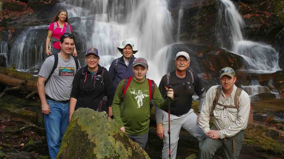 group of people posted in front of a waterfall with a rock in front of them