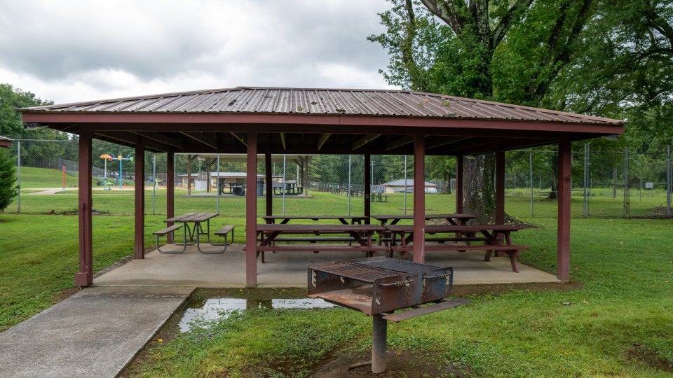 Outdoor park pavilion with picnic tables and barbecue grill.