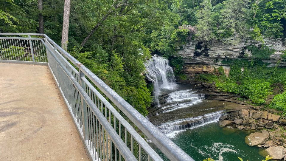 View from a bridge over a forested area with a waterfall and river.