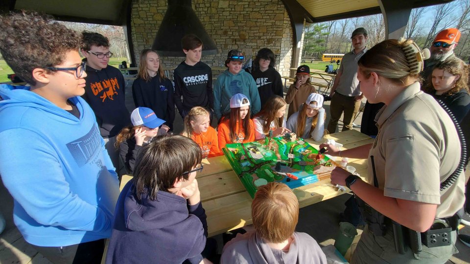 Park ranger teaching children about wildlife outdoors.