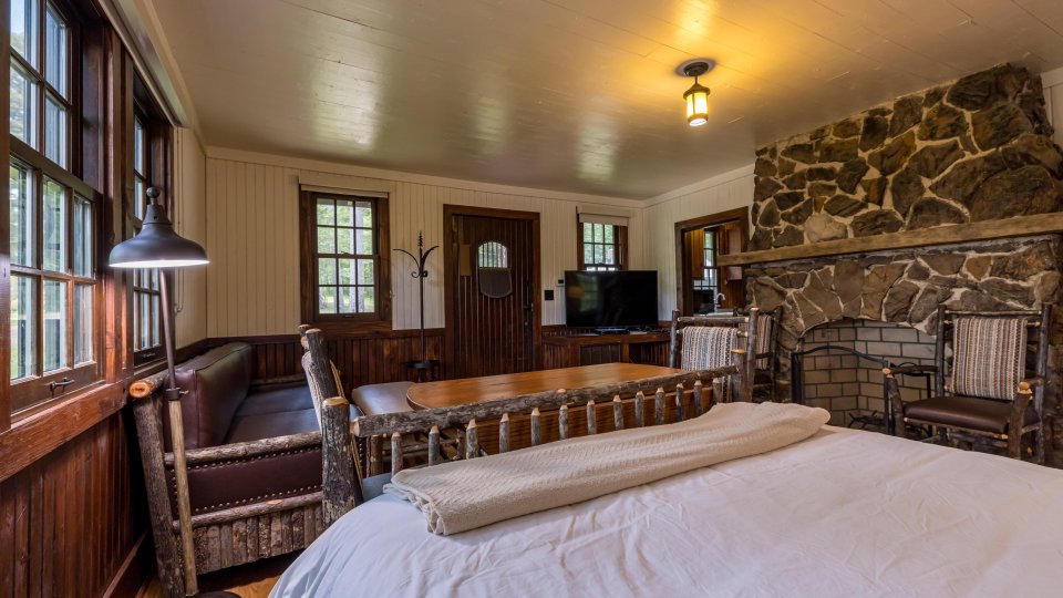 Cozy rustic bedroom with a stone fireplace and wooden furniture.