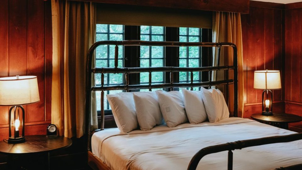Cozy wood-paneled bedroom with large bed, lamps, and curtains.