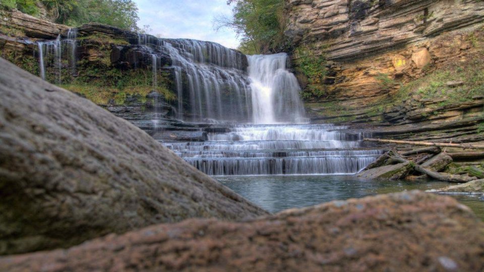 Water cascades over a rocky ledge into a serene pool below.