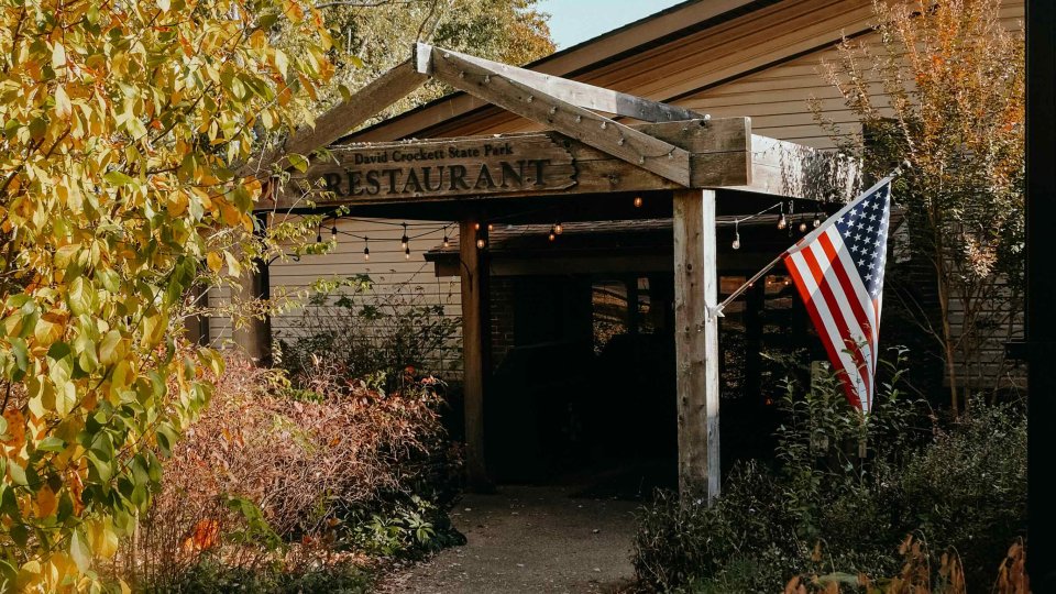 Autumnal setting with an American flag outside a rustic building.