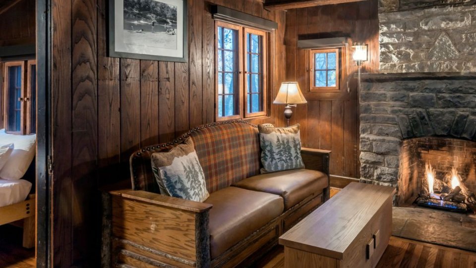 Cozy wooden cabin interior with a lit fireplace and plush seating.