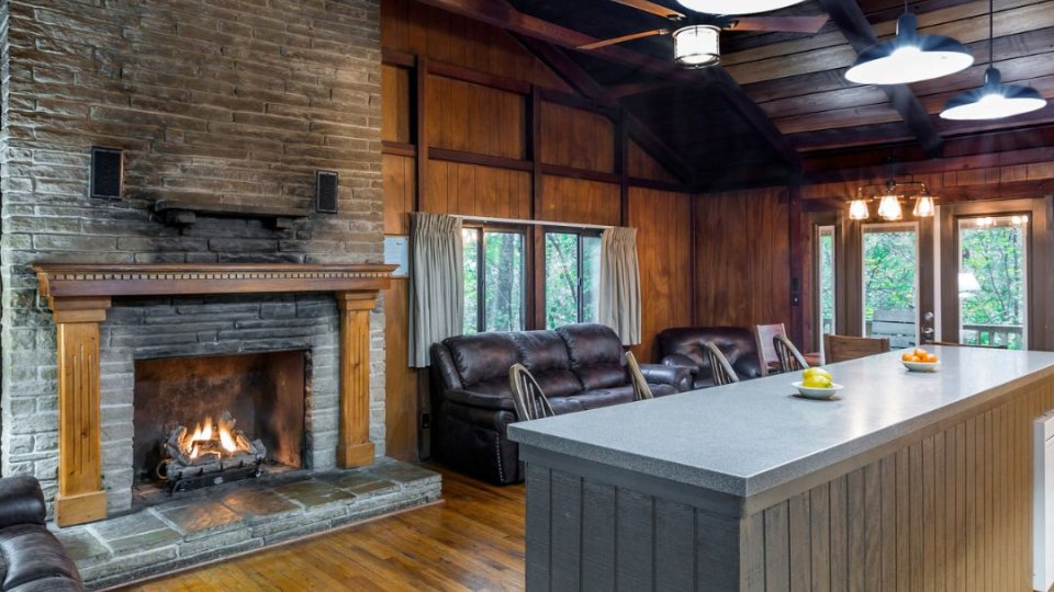 Cozy rustic living room with a lit fireplace and wooden interiors.