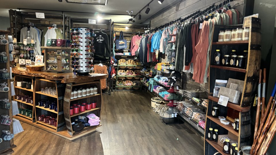 Small, cozy boutique interior with clothing and accessories displayed on wooden shelves.