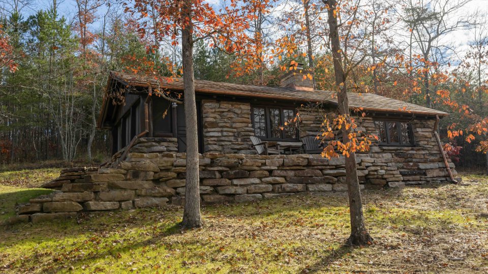 Stone cabin in a forest surrounded by trees in the fall