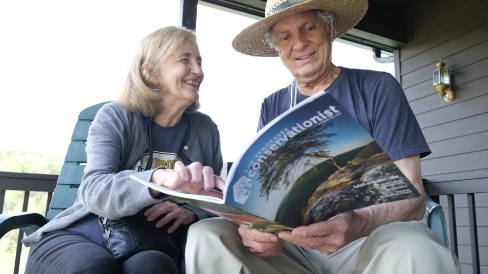 A couple reading The Tennessee Conservationist magazine outside on a porch
