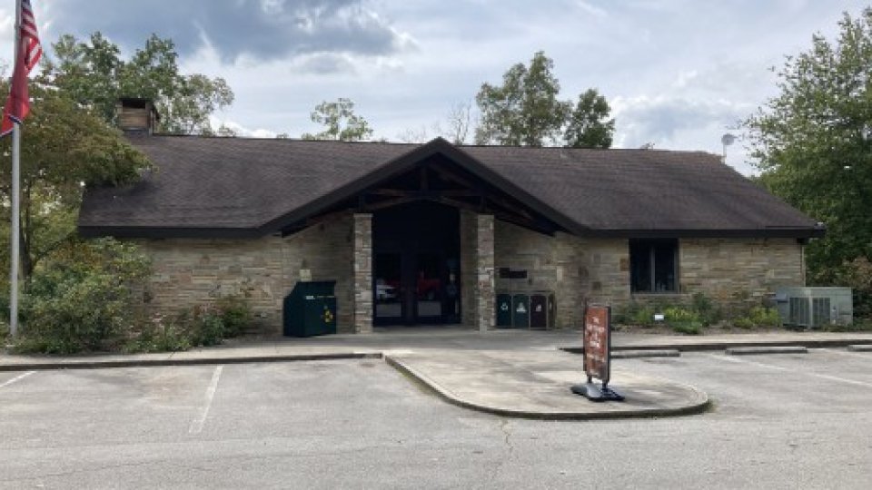 A stone-covered building, with double doors in the center, sits upon a parking lot.
