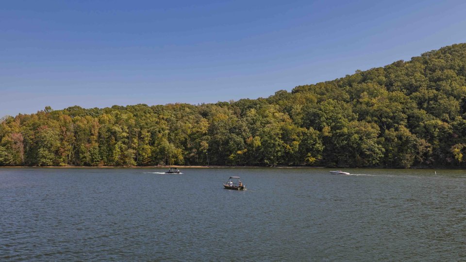 Three boats on a lake with a forested hill in the background.