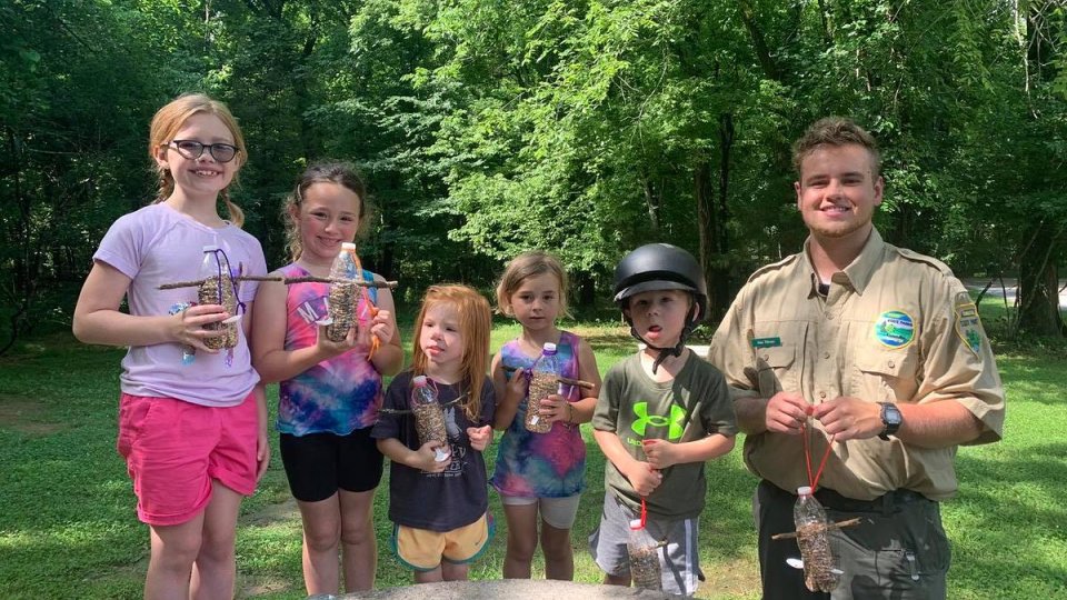 Group of children with a park ranger outdoors, some holding ice creams.