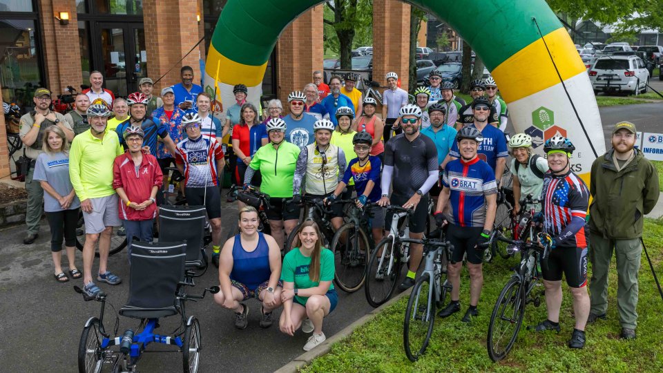 Group of bikers posing in front of inflatable sign.