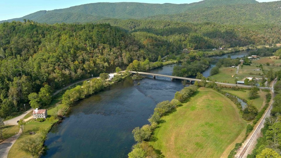 Aerial view of a winding river with a bridge and lush greenery.