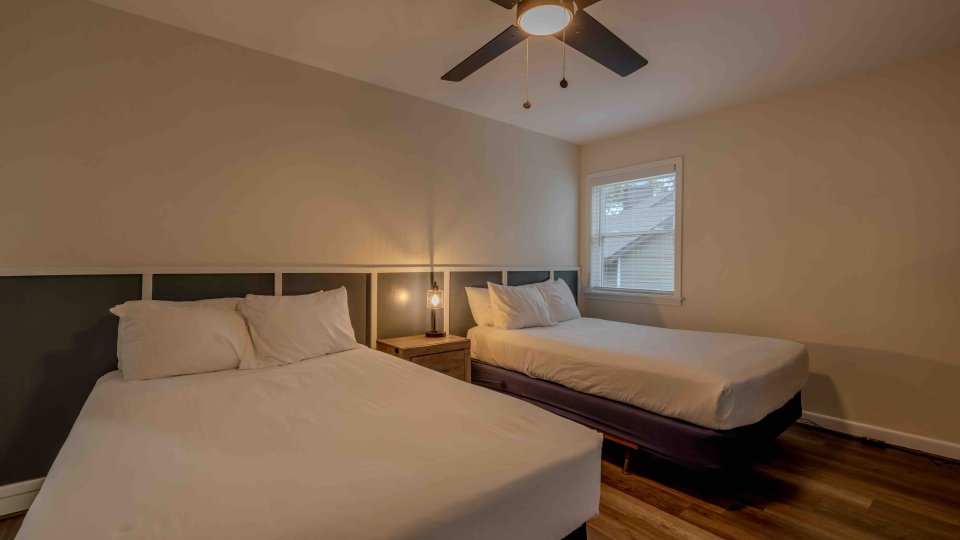 Twin beds with white linens in a serene bedroom, lamps on.