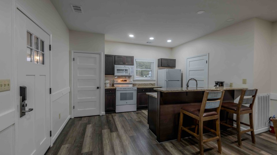 Modern kitchen with white cabinets, stainless steel appliances, and wooden dining area.