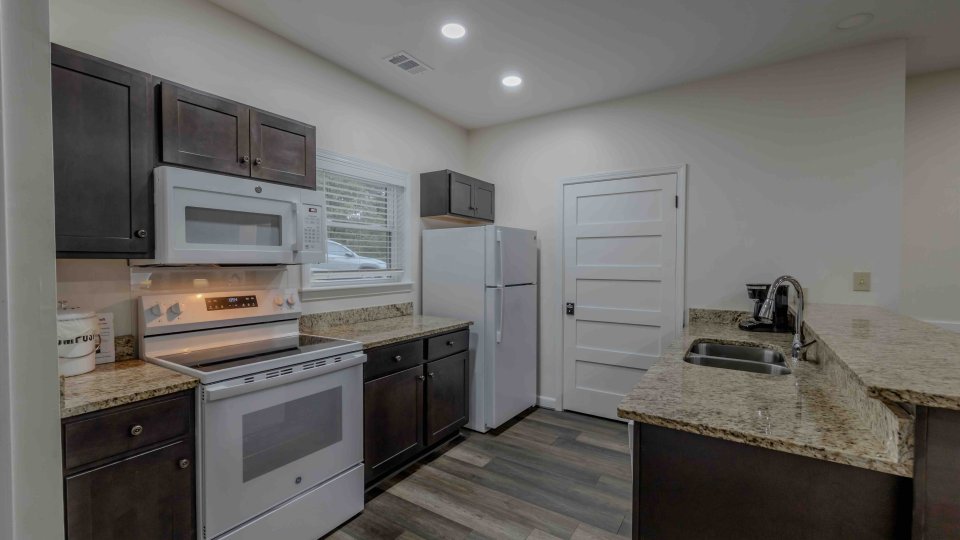 Modern kitchen with white appliances and dark wood cabinets.
