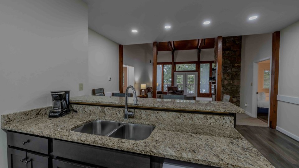 Modern kitchen interior with granite countertops and large windows.