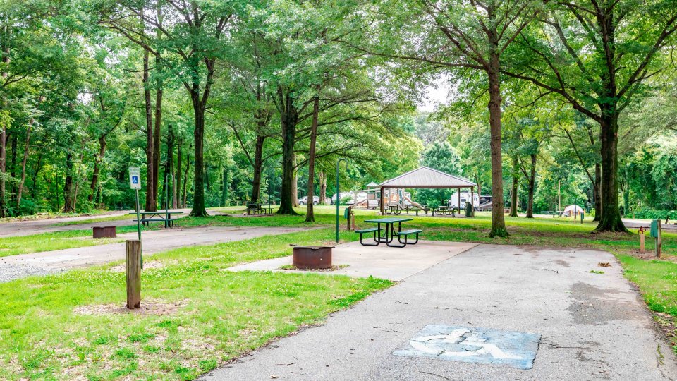 camping spot with a handicapped sign with a fire pit and picnic table.