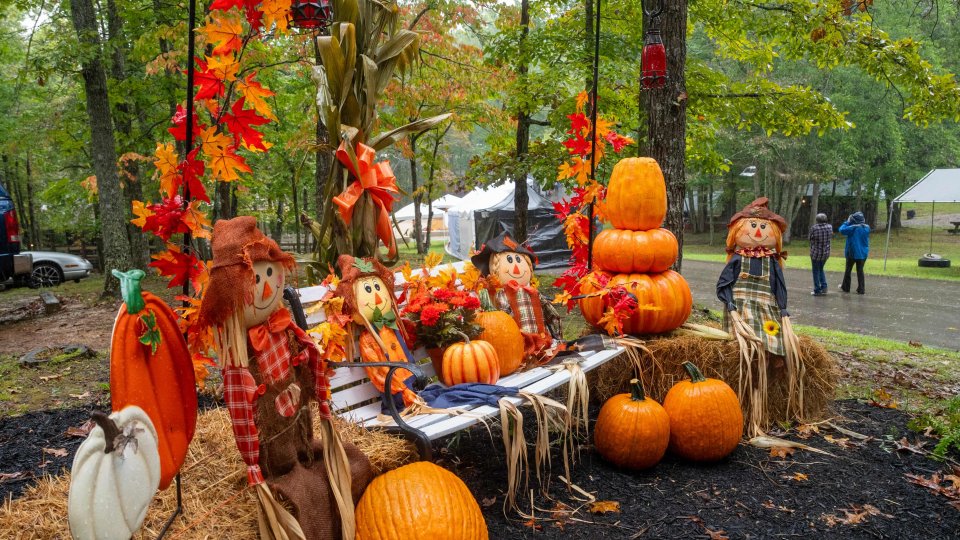 Autumn festival display with pumpkins, hay bales, and scarecrows outdoors.