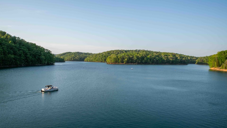 Small boat on a serene lake surrounded by lush green hills.