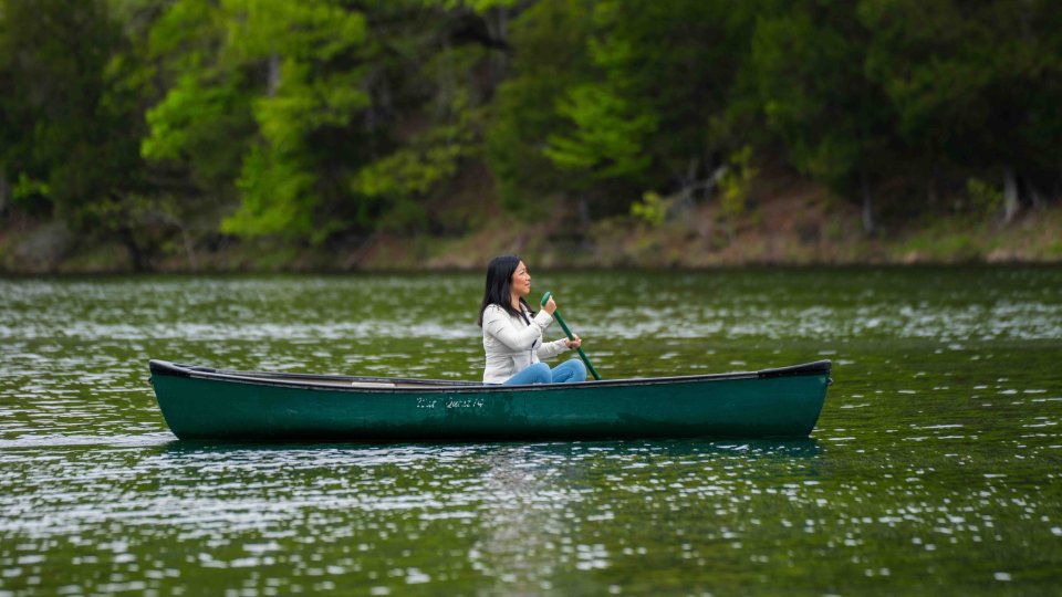Woman in boat paddling across a river