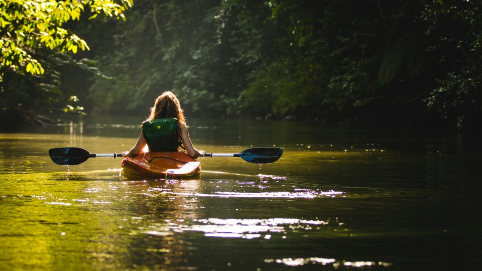 A person wearing a lifejacket paddling down a calm river