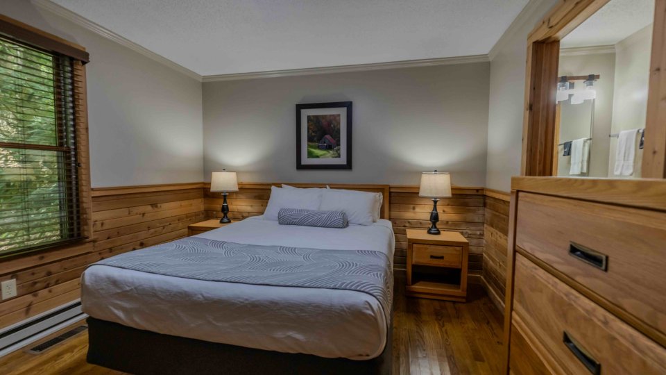Cozy bedroom with wooden furnishings, double bed, and soft lighting.