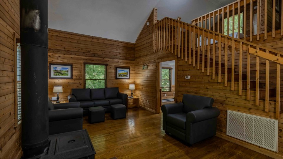 Cozy cabin interior with wooden walls, staircase, and modern furniture.