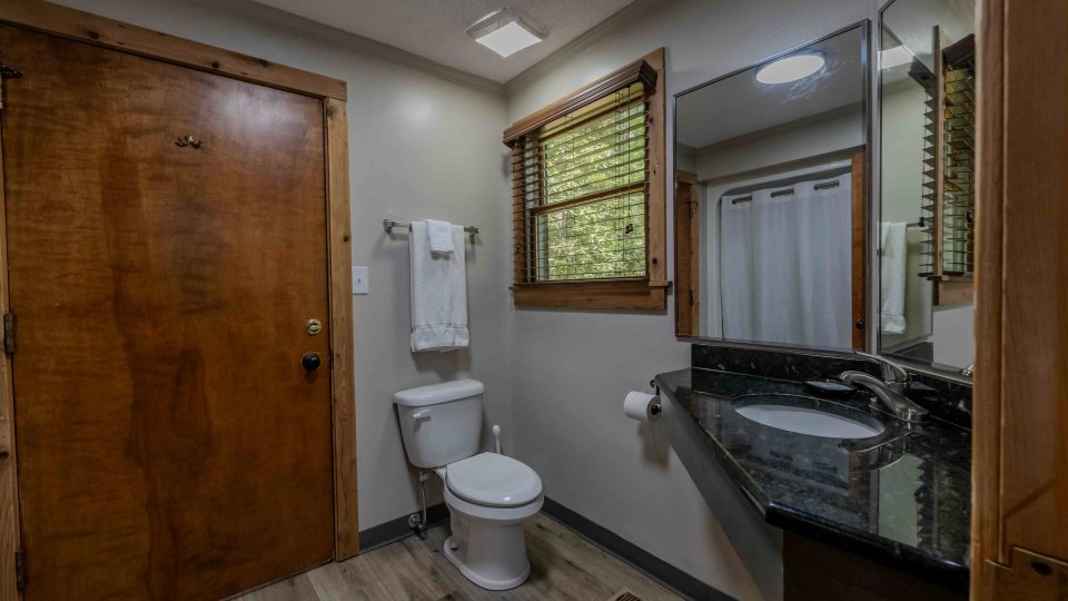 Modern bathroom interior with wooden door, vanity, and tiled floor.