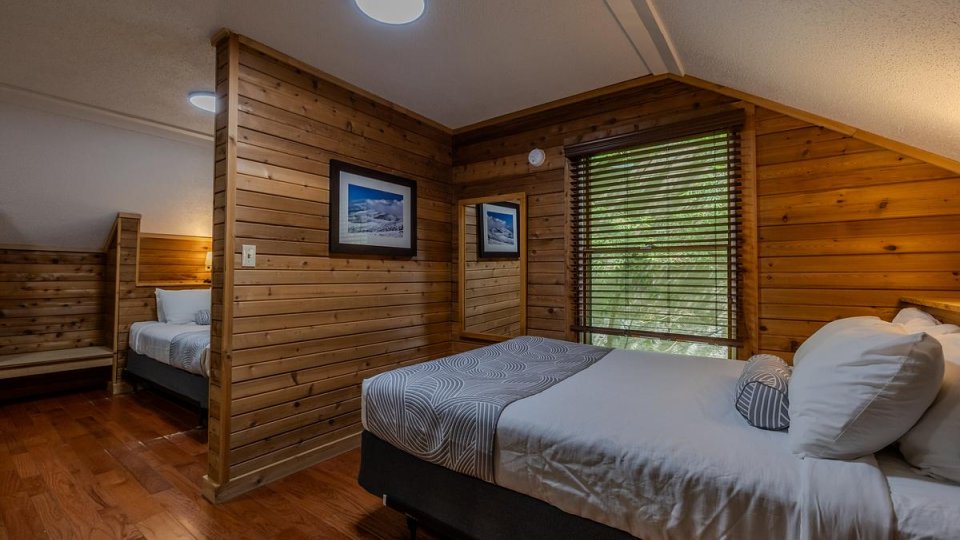Cozy cabin bedroom with wooden walls and two beds.