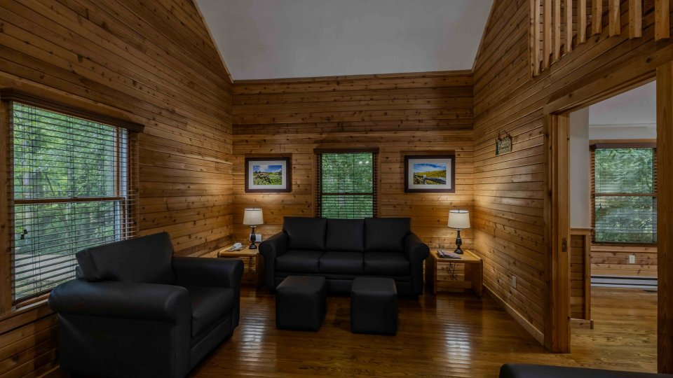 Cozy wooden cabin interior with sofas and a staircase leading upstairs.