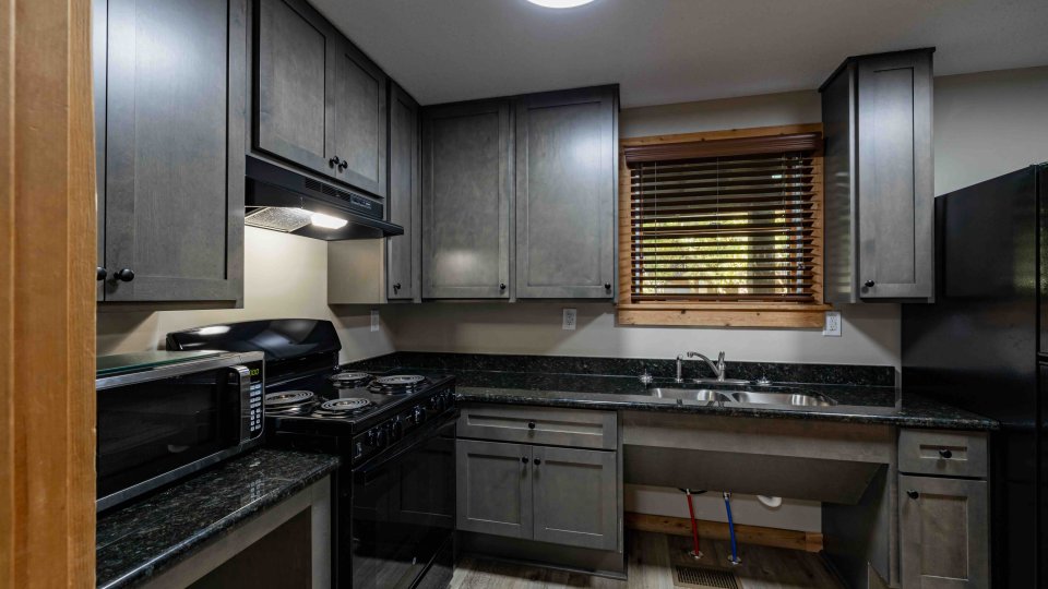 Modern kitchen with dark gray cabinets and stainless steel appliances.