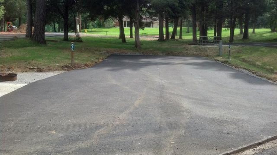 Paved driveway surrounded by trees and grass.
